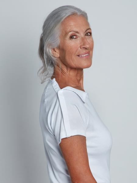 femme de profil en t-shirt blanc ouvert sur les épaules par bandes d'aimants